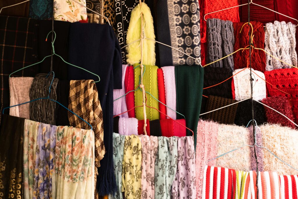 Close-up view of various colorful scarves and fabrics hanging on wire hangers.