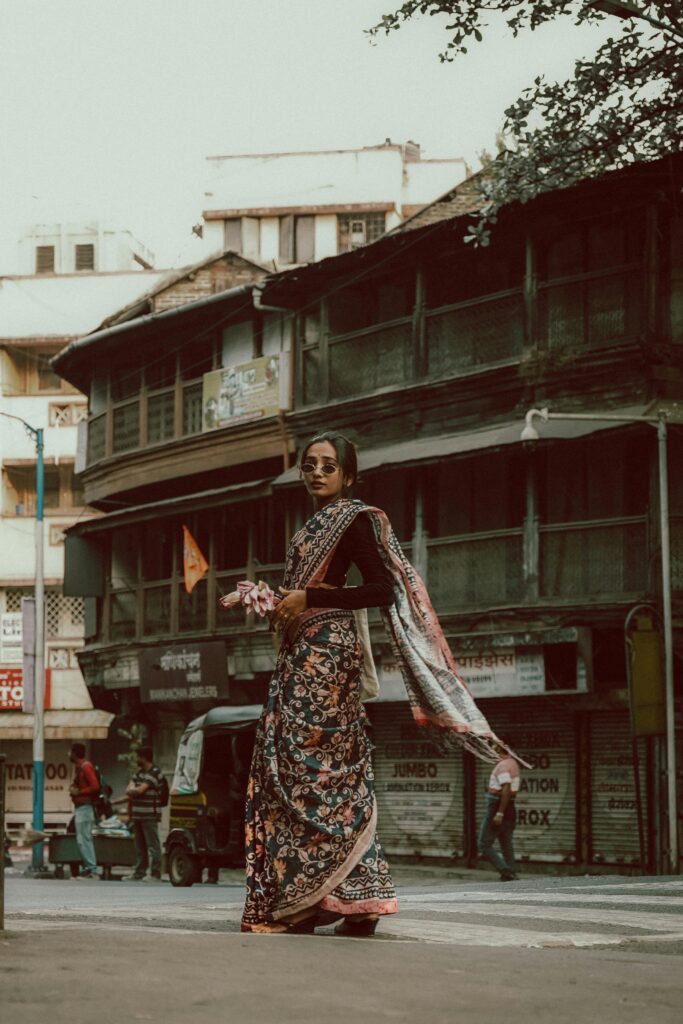 A fashionable woman in a saree walks on a traditional street in Pune, India.