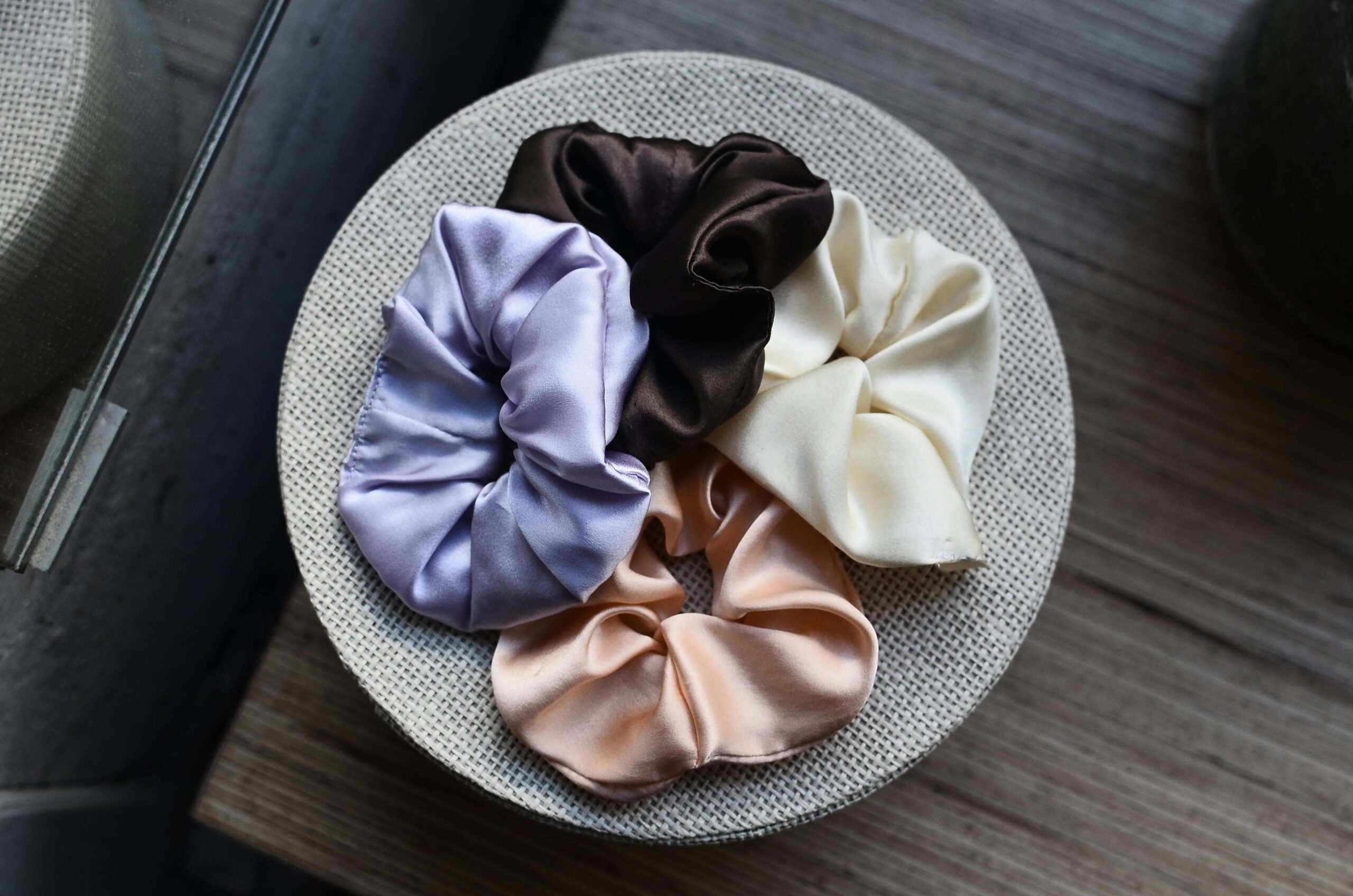 A vibrant collection of silky scrunchies displayed on a wooden surface, showcasing a modern and decorative design.